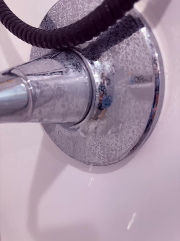 Shower faucet covered in hard-water spots before cleaning